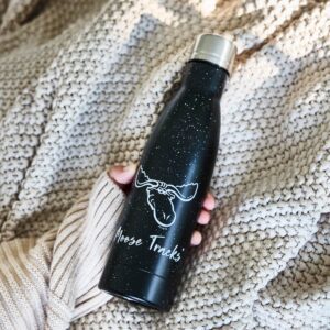 A person holding a black Moose Tracks Water bottle that reads, "Moose Tracks" and features a moose head logo on the front.