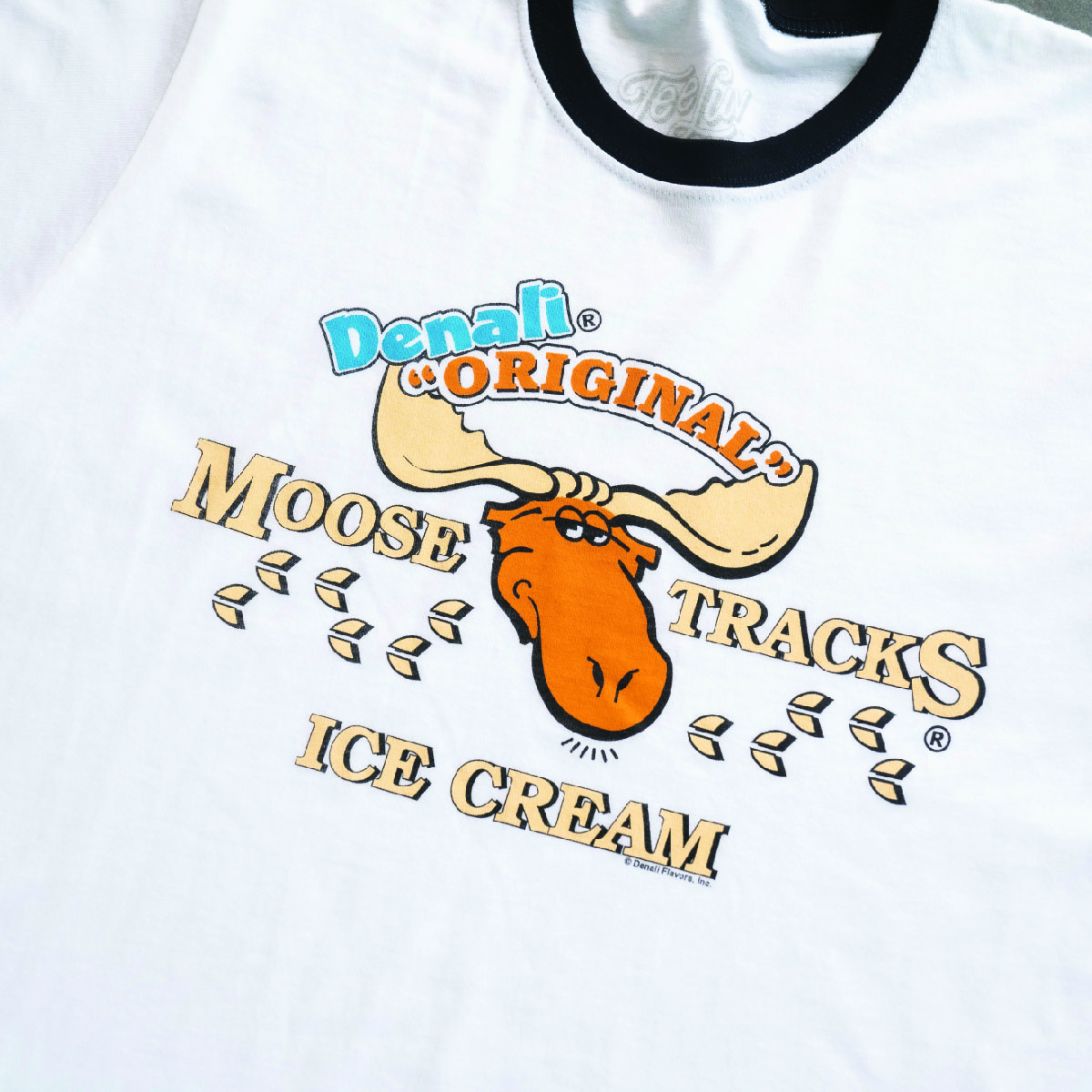 white t-shirt with black ringer banding around neck and arms. features moose tracks ice cream logo