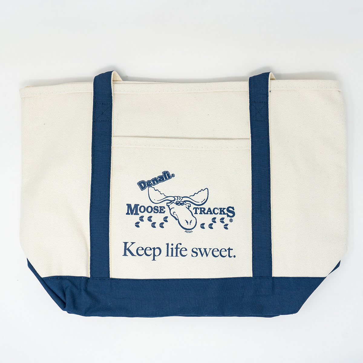 The Moose Tracks canvas tote bag, with navy detailing and a navy Moose Tracks logo and "Keep Life Sweet" screen printed in the middle.